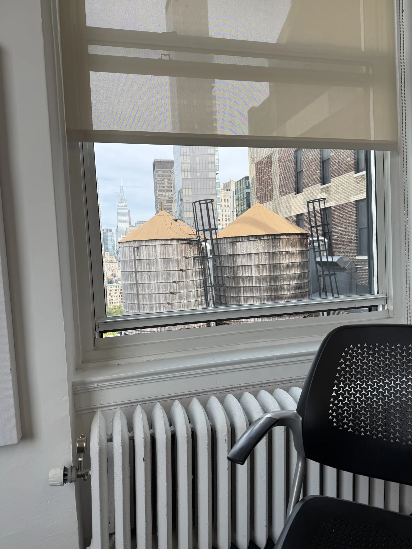 Two rooftop water towers outside a New York apartment window